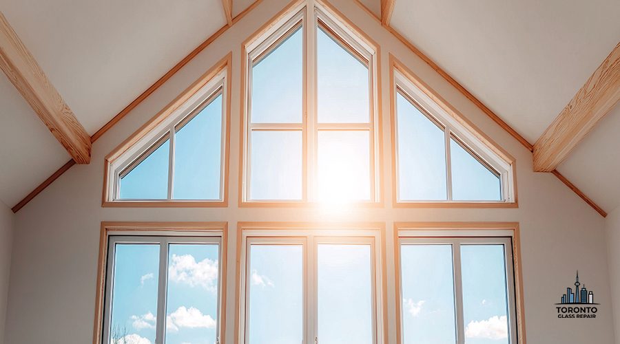 A bright, spacious room featuring large windows that allow sunlight to flood in, highlighting wooden beams and a clear sky outside.