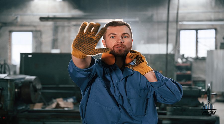 Showing stop gesture by a hand. Factory worker in blue uniform is indoors.