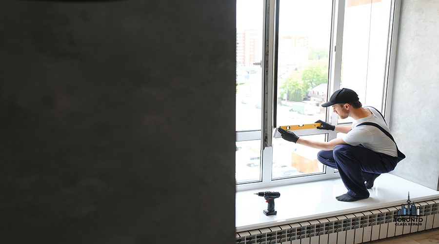 Workman in overalls installing or adjusting plastic windows in the living room at home.